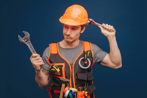 istock Curious builder in a helmet with a wrench, isolated over blue background 1315208593