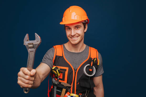 istock Smiling builder in a helmet is holding wrench, isolated over blue background 1315208601