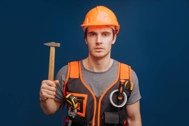 istock Serious builder in a helmet with a hammer, isolated over blue background 1315208605