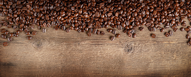 Coffee beans border on dark wooden background. Copy space, overhead.