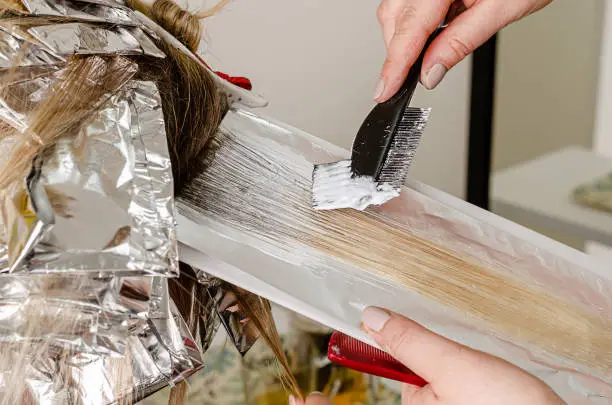 Process of applying bleaching powder on clients hair and wrapping into the foil. Ombre hairstyle technique