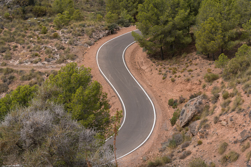 road in southern Spain, there are white lines on the road, there are trees, bushes and grass, there are rocks