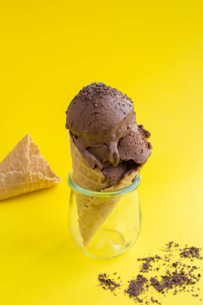 istock Chocolate ice cream in a waffle cone on the yellow  background 1315216794