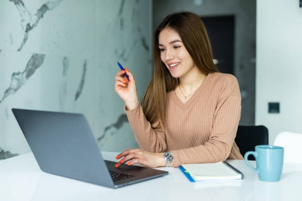 istock Confident woman using laptop, writing taking notes, sitting at wooden table in modern kitchen, student watching webinar, studying online, businesswoman freelancer working on project at home 1315217706