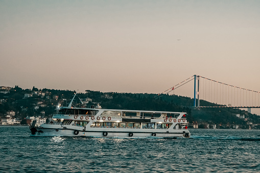 A ferry goes under the bridge on Istanbul Bosphorus at evening un