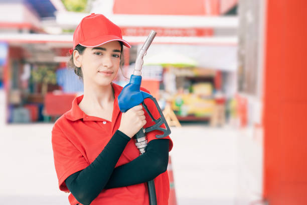 femmes heureuses de personnel de station-service de portrait avec le sourire avec la buse de carburant pour le travail de service de remplissage d’essence de voiture. - gasohol photos et images de collection