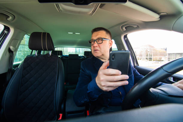 istock Middle aged man with eyeglasses sitting in his car and reading message on smart phone while witting in traffic. 1315223233