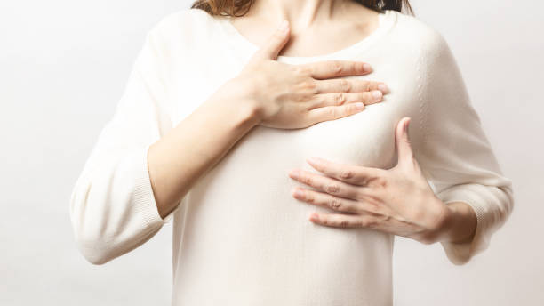 여자는 백색 배경에 유방암의 표시를 위해 그녀의 유방에 덩어리를 검사합니다. 헬스케어 개념. 암 자체 검사; 건강한 소녀. - breast chest the human body human skin 뉴스 사진 이미지