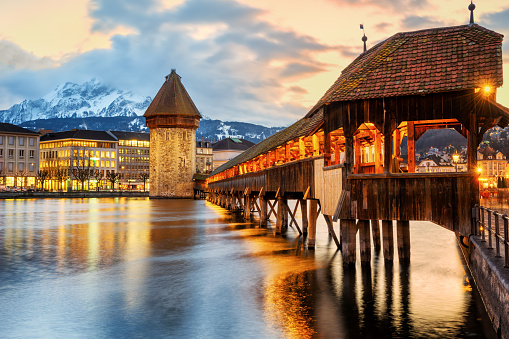 Lucerne city, Switzerland, view of the wooden Chapel bridge and Mount Pilatus on a winter evening in sunset light