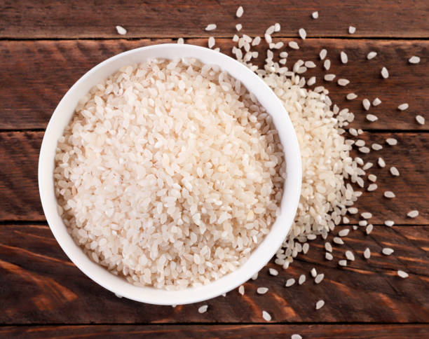 istock Rice in plate and sprinkled on a wooden background. Top view. 1315229094