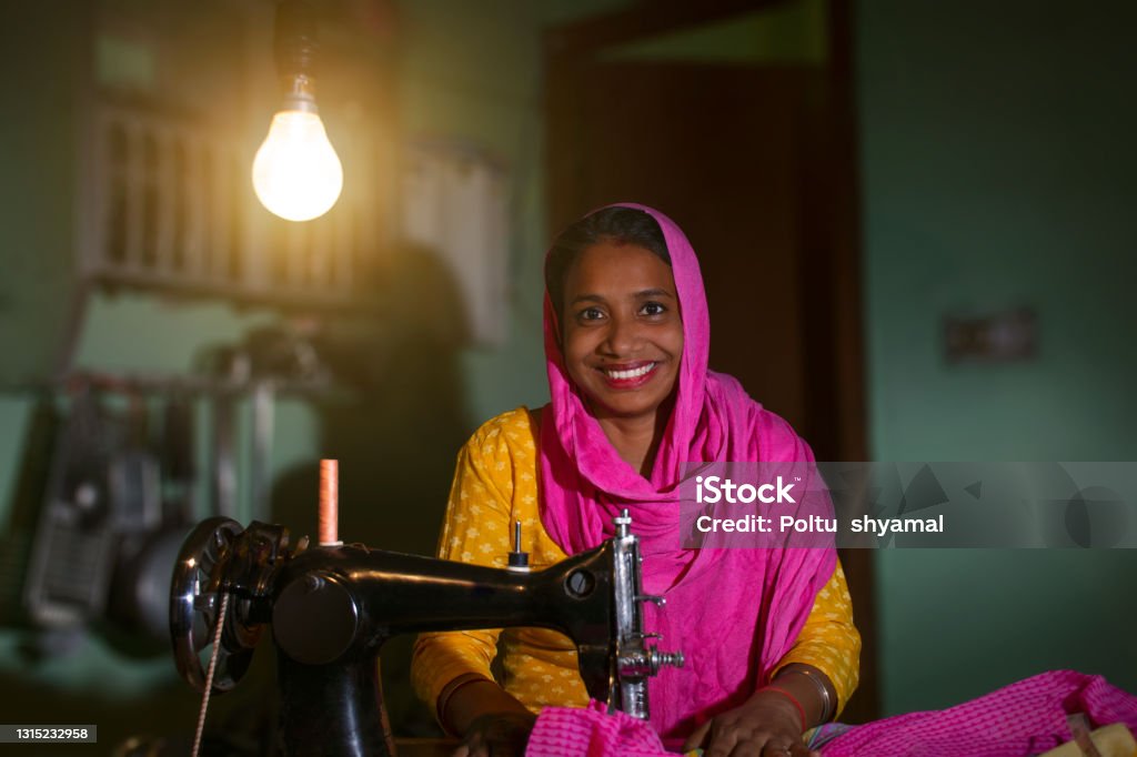 PORTRAIT OF A RURAL WOMAN SEWING CLOTHES India Stock Photo