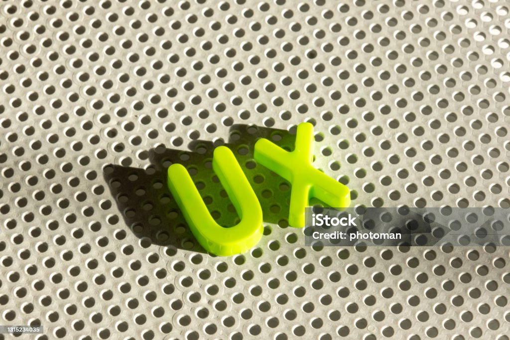 UX word composed with green abc alphabet letters, copy space Meaningful words with single letters concept: Collection of plastic ABC learning toy letters on grey board. Light creating shadows. Creative design with copy space User Experience Stock Photo