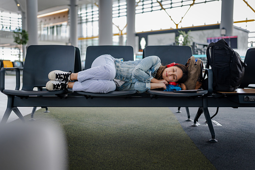 Young Woman waiting for delayed flight and sleeping on chairs