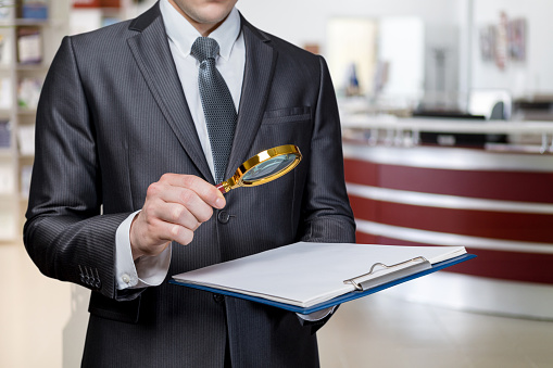 Criminal investigation study concept. Lawyer examining a document with a magnifier on a blurred background.