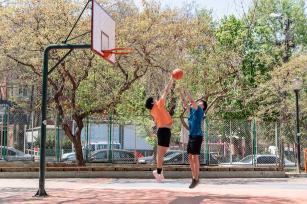 jovens adultos asiáticos jogando basquete ao ar livre - basketball child dribbling basketball player - fotografias e filmes do acervo