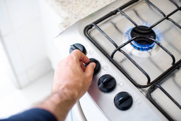 Cooking gas - lighting stove Hands of a man turning knob to light a gas stove cooktop stock pictures, royalty-free photos & images