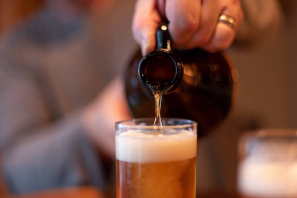 крупным планом крафтового пива, выливаемого из рычака - amber beer стоковые фото и изображения