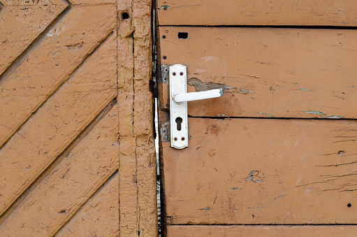 Close-up of open door and door handle with a key and a keychain shaped house
