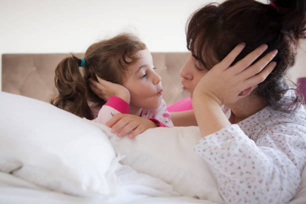 istock Mother and daughter kiss on their bed 1315242594