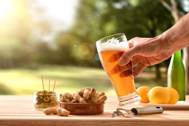 uomo che fa uno spuntino in campagna con birra in mano - beer nuts foto e immagini stock