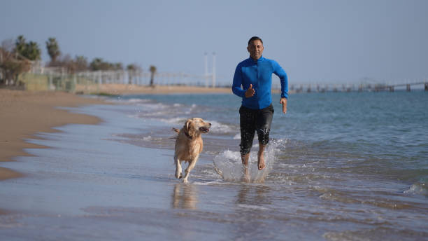 istock Man running on the beach with his dog 1315254970