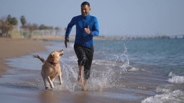 istock Man running on the beach with his dog 1315254994