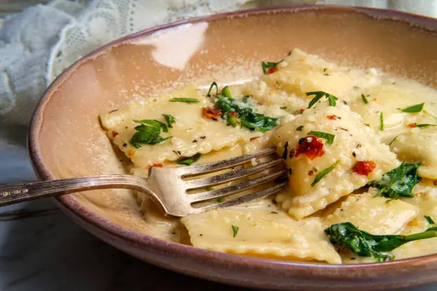 Cheese ravioli in a Tuscan creamy sauce with spinach and crushed red pepper