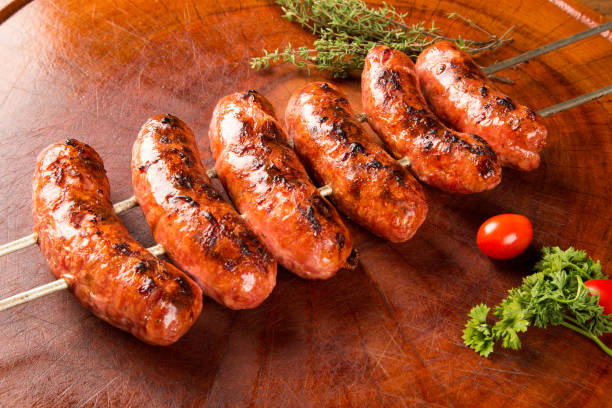istock Sausages on the barbecue spit on wooden background 1315256232