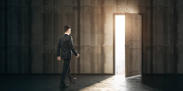 istock Businessman walking towards exit in a dark concrete room. Leadership and future concept 1315257072