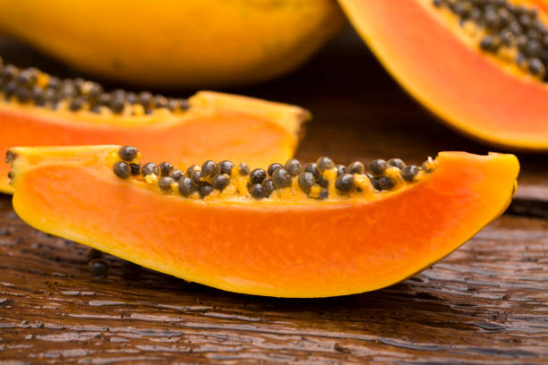 istock Sliced fresh papaya on wooden background 1315259342