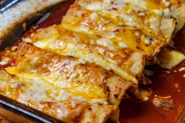 Mexican Enchiladas Dinner Cooking traditional Mexican enchilada dinner in glass casserole dish enchilada stock pictures, royalty-free photos & images