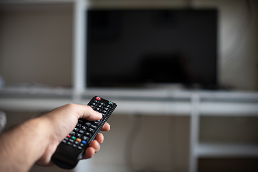 Pointing remote control towards a TV at home - watching TV - TV off