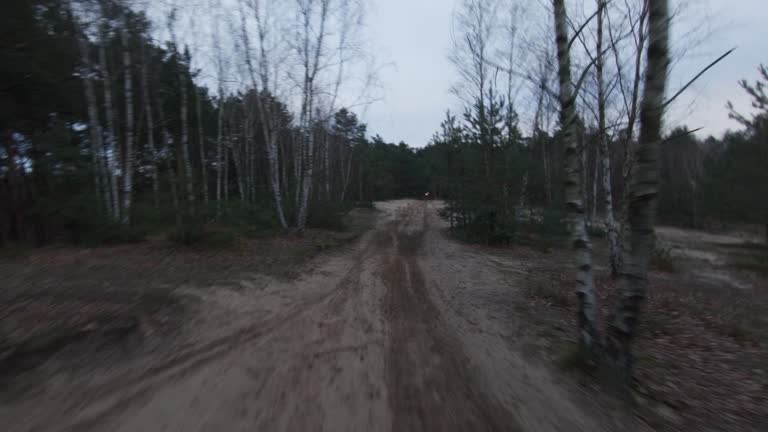 Motocross race at dusk. Driver speeding on cross country terrain. FPV - Racing drone view. Drivers POV