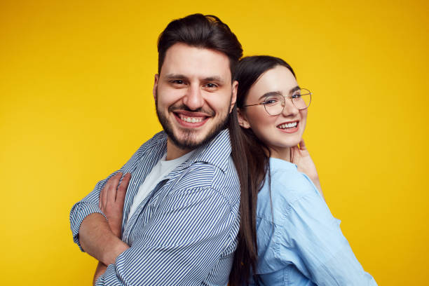 istock Couple stands backs and smiling against yellow background 1315261255
