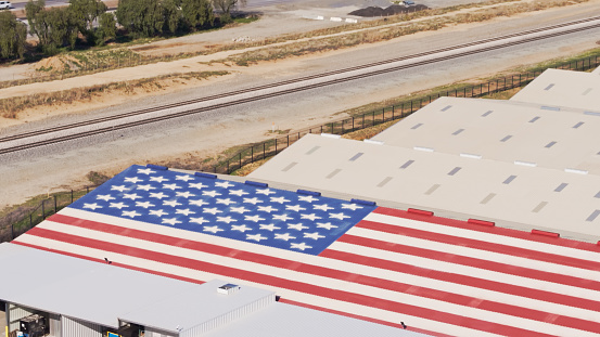 Aerial drone still of a warehouse with a huge American flag painted on its roof in Banning, Riverside County, California.