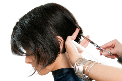 Young lady cutting hair at the hairdresser isolated on white background.
