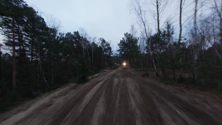Motocross race at dusk. Drivers speeding on cross country terrain. FPV - Racing drone view.