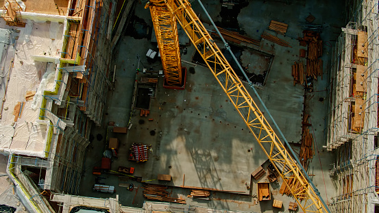 Aerial shot looking down on a crane and the construction site surrounding it.