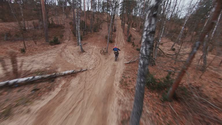 Enduro motorcycle race. Driver speeding on cross country terrain. FPV - Racing drone view.