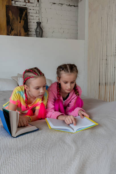 istock Girlfriends read book lying on bed in room home. Concept education is process teaching at school. Vertical 1315294536