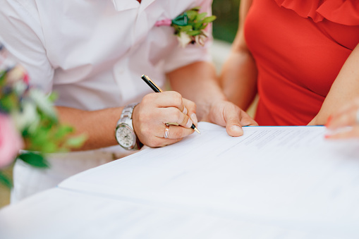 The groom signs the wedding certificate during the wedding ceremony, close-up. . High quality photo