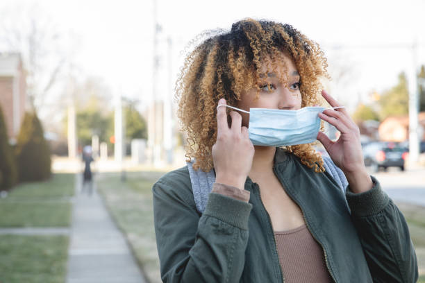 istock Woman taking mask off while walking outdoors 1315300652