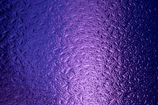 Abstract background made of corrugated purple glass.Glass background.