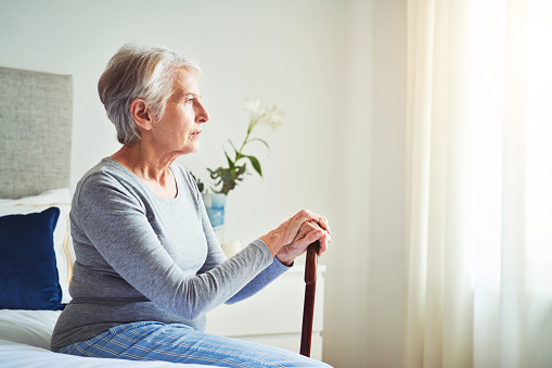 Foto de una mujer mayor mirando pensativo mientras sostenía un bastón en casa photo