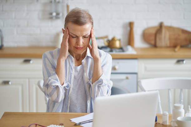 istock Frustrated mature woman suffering from headache while working online from home 1315325643