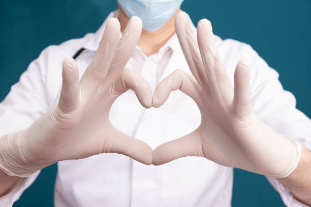 il medico ha fatto un cuore di mani, su uno sfondo blu - surgeon isolated paramedic operating room foto e immagini stock