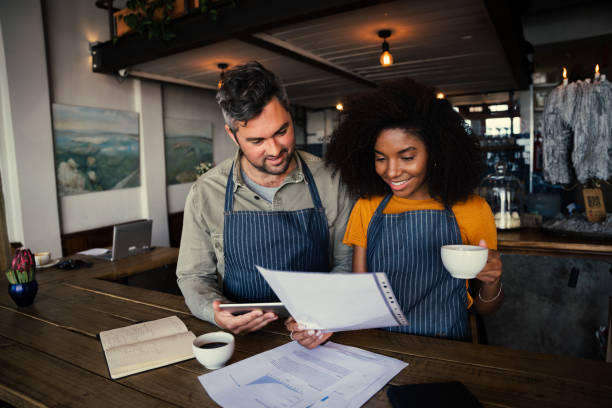 istock Colleagues discussing paper work drinking hot coffee in coffee shop 1315333453