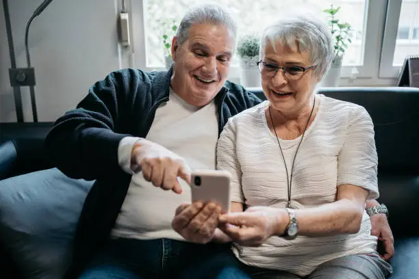 Elderly couple looking at a smart phone laughing