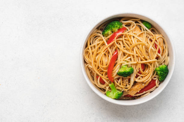 Egg noodles with broccoli and red bell peppers Egg noodles with broccoli and red bell peppers in bowl. Stir fry noodles with soy sauce and sesame seeds sesame photos stock pictures, royalty-free photos & images