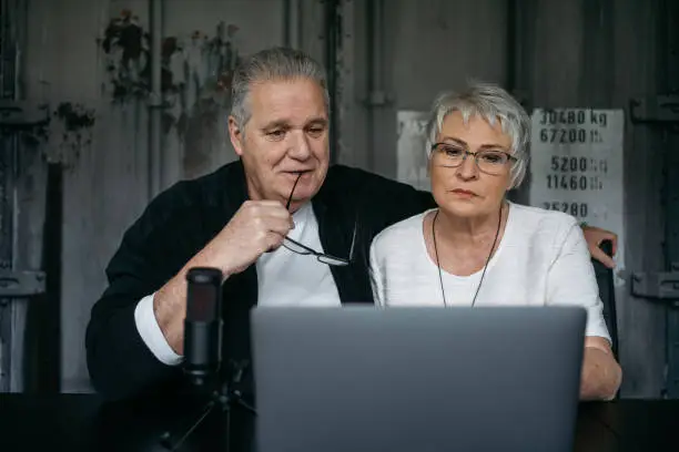 Elderly couple communicating via laptop and using a microphone